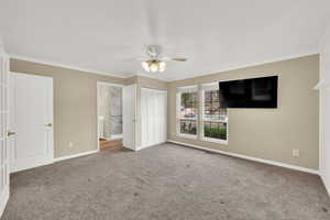 Unfurnished bedroom featuring crown molding, carpet floors, a ceiling fan, and a closet