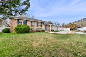 Bi-level home featuring brick siding, a chimney, a garage, concrete driveway, and a mountain view