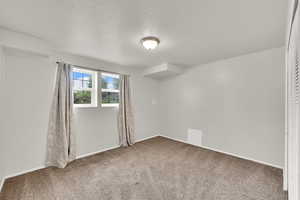 Unfurnished room with a textured ceiling and carpet floors