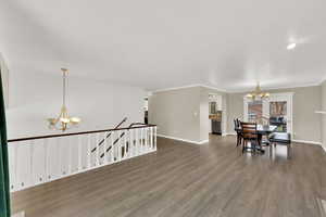 Dining space with suspended lighting, wood finished floors, and crown molding