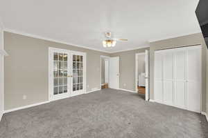 Unfurnished bedroom featuring french doors, crown molding, carpet flooring, a closet, and ceiling fan