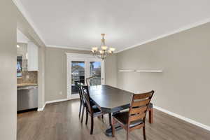 Dining space with light wood-style floors, hanging lights, and crown molding
