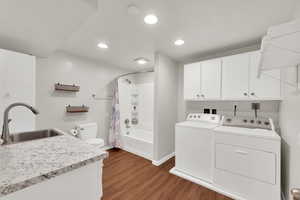 Laundry area featuring dark wood finished floors, washer and dryer, and recessed lighting