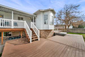 Wooden deck featuring a covered hot tub and stairs