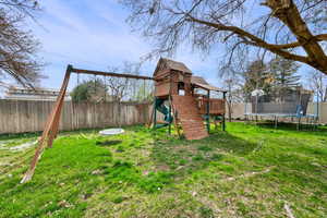 View of jungle gym featuring a trampoline and a fenced backyard