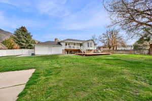 Back of house with a fenced backyard, a deck, brick siding, and a chimney