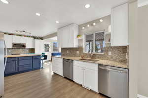 Kitchen featuring open shelves, stainless steel appliances, dual tone cabinetry, light wood-style floors, and decorative backsplash