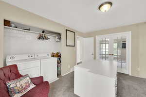 Laundry area with french doors, light colored carpet, and washing machine and dryer