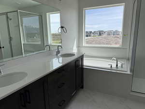 Full bathroom with a stall shower, a bath, double vanity, and light marble finish flooring