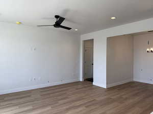 Spare room featuring a ceiling fan, light wood-type flooring, a textured ceiling, and hanging lights