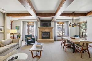 Living area with light carpet, a glass covered fireplace, and beamed ceiling