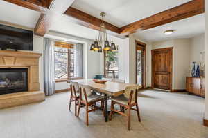 Dining room featuring light carpet, a glass covered fireplace, and beam ceiling