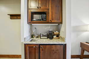 Bar featuring light stone countertops and black microwave