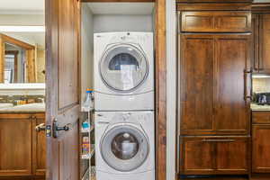 Laundry area with stacked washer and clothes dryer and a sink
