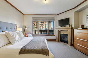 Bedroom with carpet flooring, a premium fireplace, and crown molding