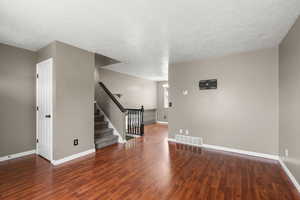 Unfurnished living room with a textured ceiling and dark wood-style flooring
