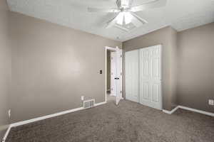 Alternate view of upstairs bedroom highlighting spacious layout, large closet, and neutral finishes. Plush carpet and ceiling fan create a comfortable, move-in ready space with flexible use.