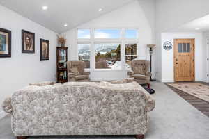 Living area with lofted ceiling, recessed lighting, and carpet