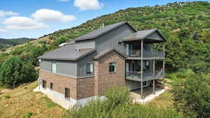 Rear view of house featuring brick siding, a metal roof, a mountain view, and a forest view