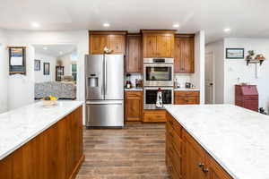 Kitchen with wood finish cabinets, stainless steel appliances, wood tiled floors, backsplash, and recessed lighting