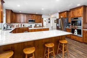 Kitchen featuring a breakfast bar area, wood finish cabinets, stainless steel appliances, and recessed lighting