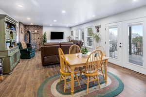Dining space featuring wood finished floors, french doors, recessed lighting, a wood stove, and brick wall