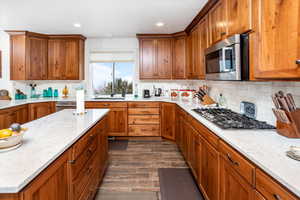 Kitchen with wood finish cabinetry, stainless steel appliances, light stone counters, and recessed lighting