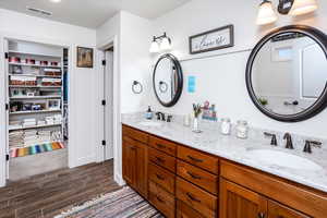 Bathroom with double vanity, wood finish floors, and a walk in closet