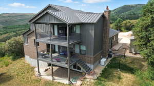 Rear view of property featuring board and batten siding, brick siding, a mountain view, and a balcony
