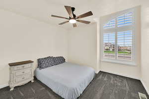 Bedroom with dark colored carpet and a ceiling fan