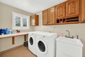 Laundry room with independent washer and dryer, light tile patterned floors, and cabinet space