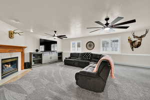 Carpeted living area with a tiled fireplace, a ceiling fan, and a textured ceiling