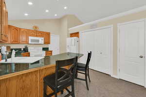 Kitchen featuring white appliances, a kitchen breakfast bar, wood finish cabinets, a peninsula, and light tile patterned floors