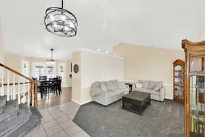 Living area featuring suspended lighting, light tile patterned flooring, vaulted ceiling, and light colored carpet