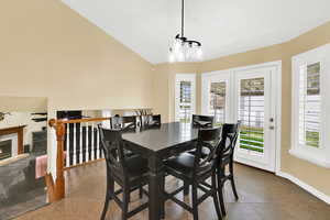 Tiled dining space featuring a tiled fireplace and lofted ceiling
