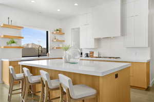 Dual tone kitchen with modern cabinets, a kitchen island, open shelves, decorative backsplash, and dual tone cabinetry