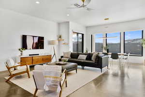 Living room with concrete flooring, a ceiling fan, and recessed lighting