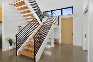 Staircase featuring a high ceiling and concrete floors