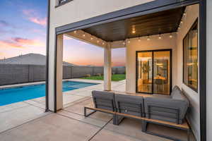 Pool at dusk with a patio area, a fenced backyard, and an outdoor hangout area