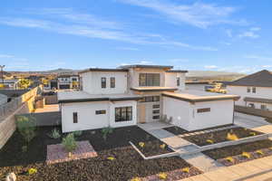 View of front of home with stucco siding, stone siding, a mountain view, and a residential view