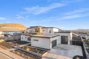 Contemporary home with a mountain view, stucco siding, an attached garage, and concrete driveway