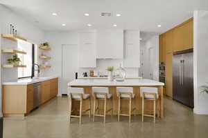 Kitchen featuring finished concrete flooring, stainless steel appliances, a kitchen bar, a center island, and open shelves