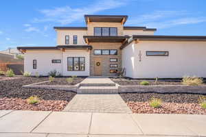 Contemporary home featuring stone siding, stucco siding, and a porch