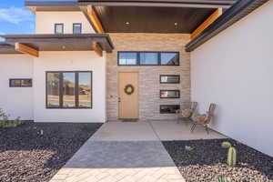 Property entrance with stone siding, stucco siding, and a tile fireplace