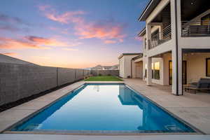 View of swimming pool featuring patio surround, a fenced backyard, and a balcony
