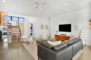 Living room with concrete floors, a ceiling fan, and recessed lighting