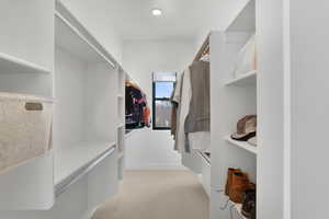 Walk in closet with light colored carpet