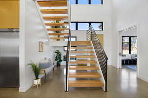 Stairway featuring finished concrete flooring, elevator, and a high ceiling