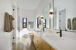 Bathroom with a freestanding bath, double vanity, finished concrete flooring, and a shower stall