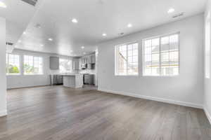 Expansive open-concept living area featuring wood-finish flooring, recessed lighting, and large windows with grid patterns